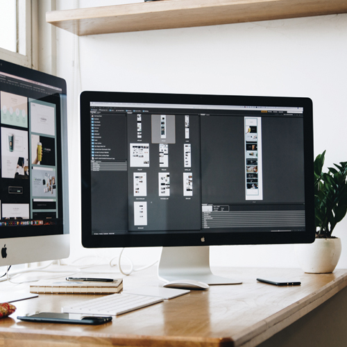 2 MAC computers on a desk, showing folders with pictures
