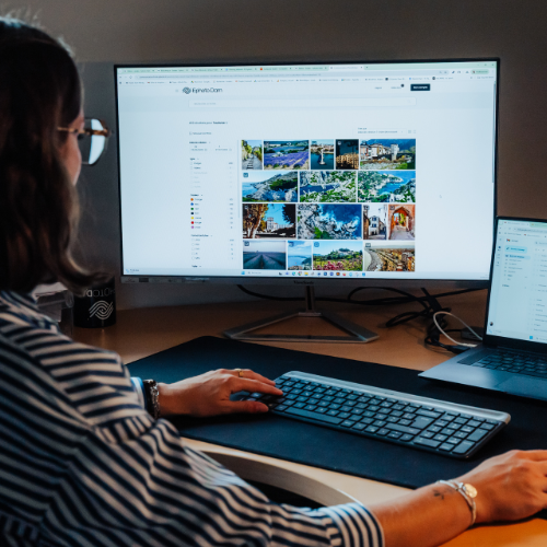 A person working at a desk looking at two screens in front of them.
