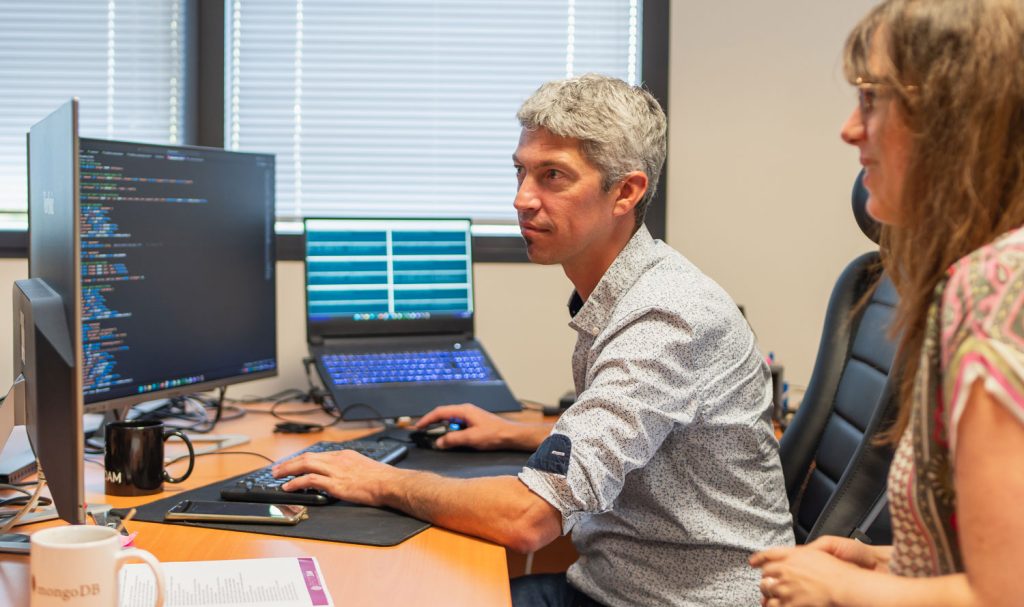 2 people sitting at a desk looking at a screen