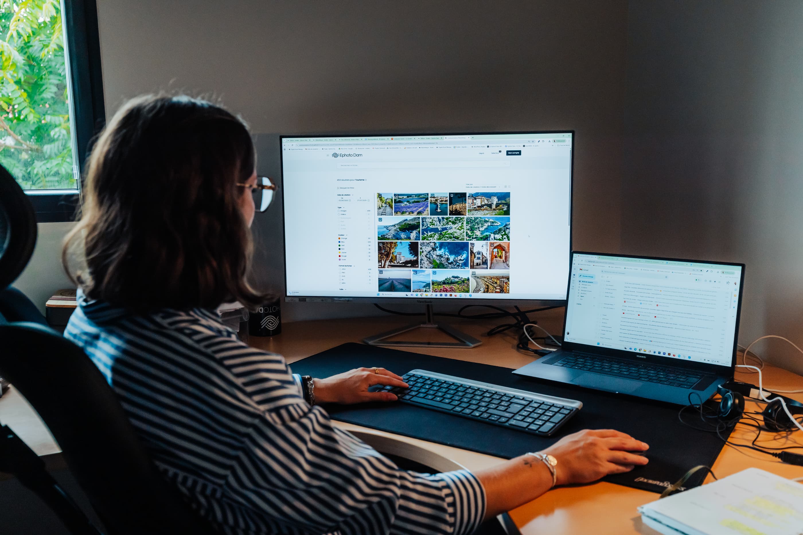Woman looking at a screen in front of her and touching the computer keyboard and mouse with her hands.