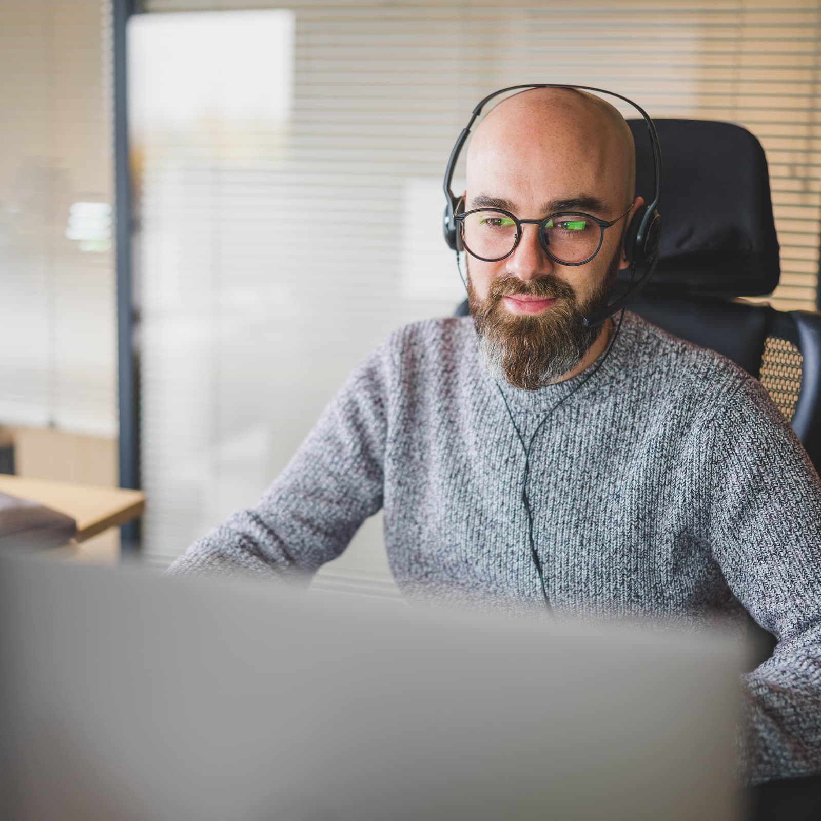 Bearded man with glasses working at a computer, illustrating advanced digital asset management with Ephoto Dam.