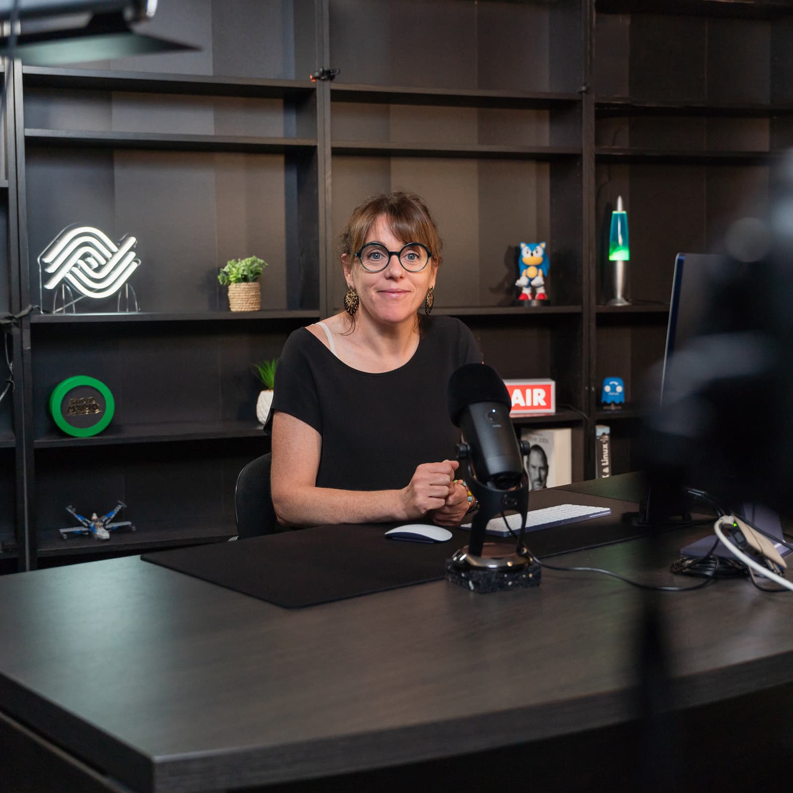 Seated woman smiling at a camera filming her in a professional video studio for the Ephoto Dam photo library solution.