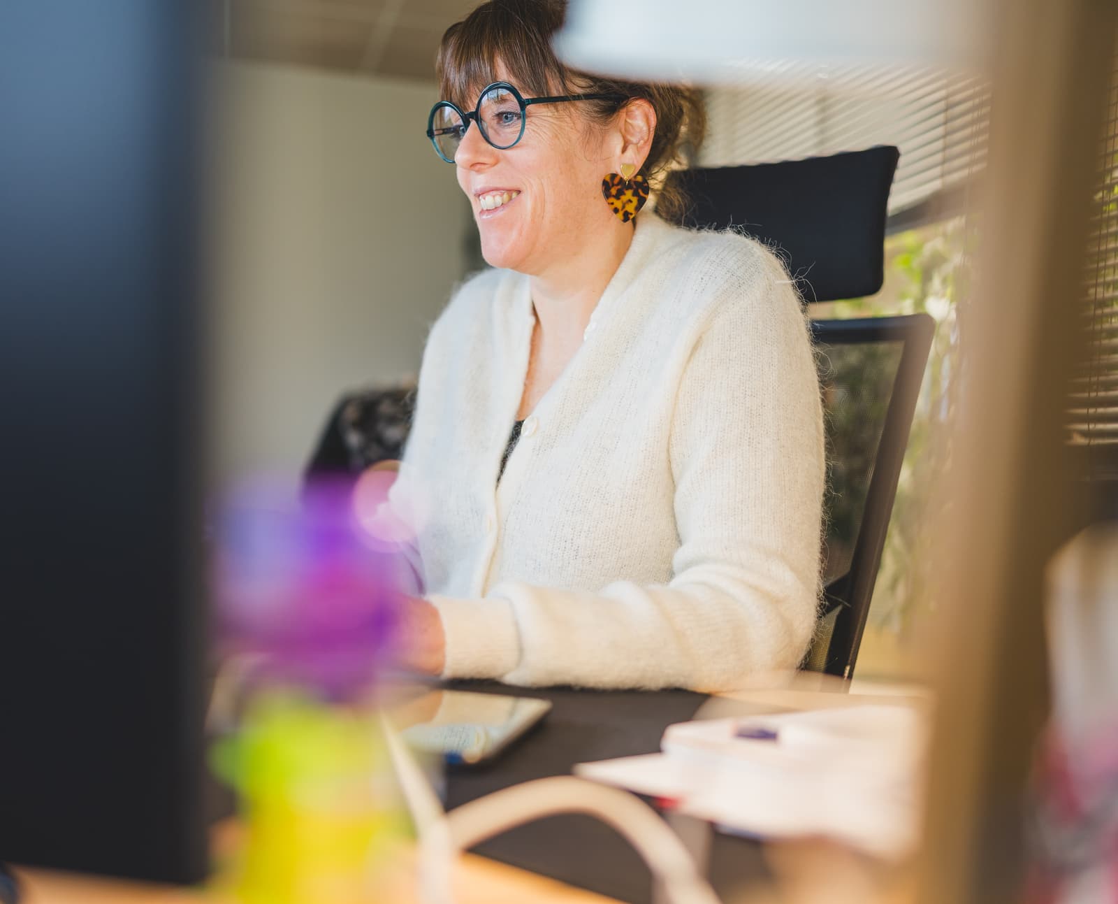 Smiling woman working on a computer, illustrating the support provided for learning the functionalities of the Ephoto Dam photo library management software.