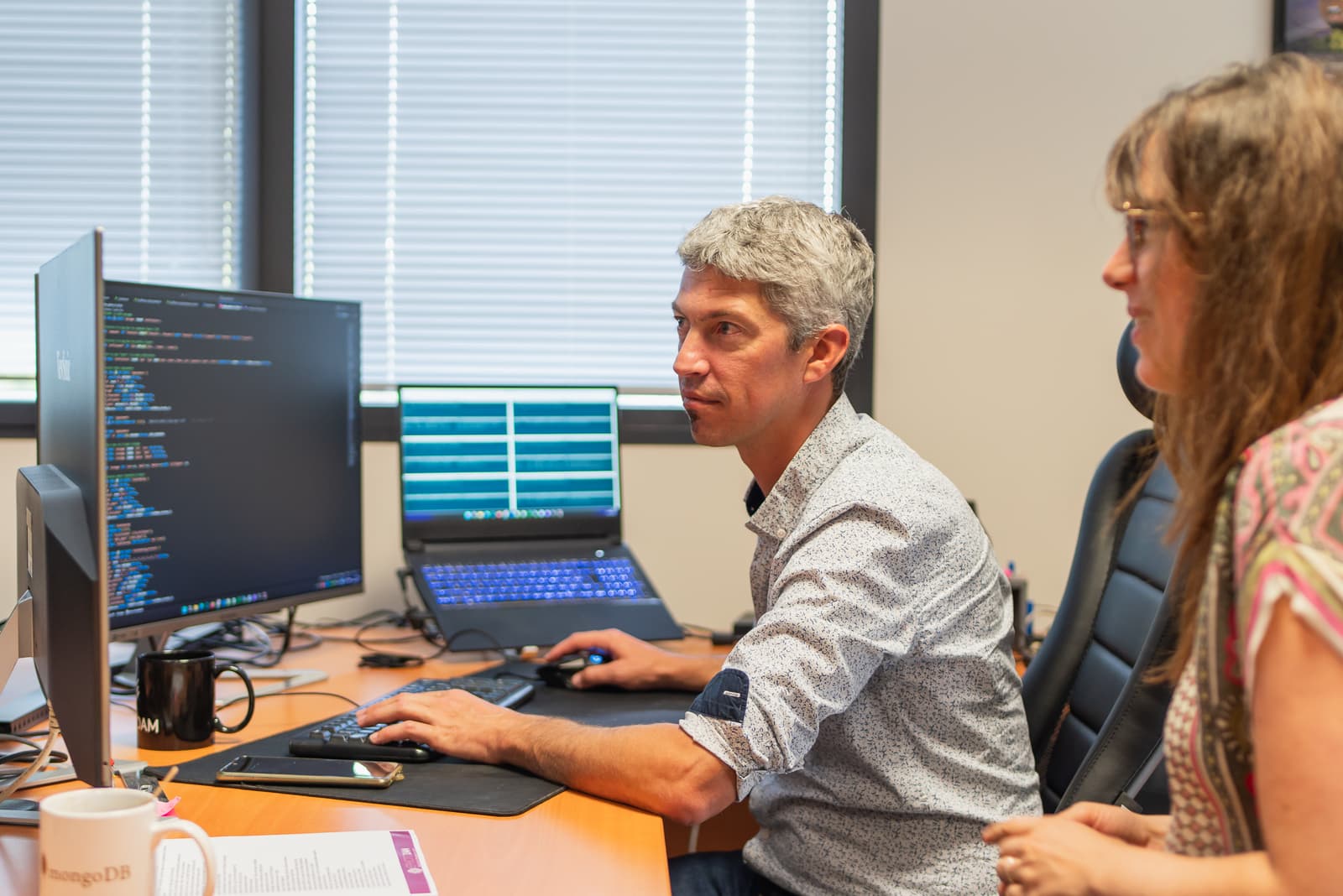 A man and a woman looking at a computer screen with HTML code.