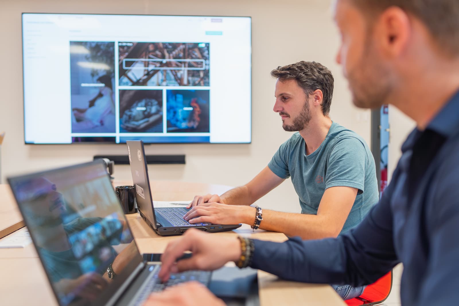 Two men in a meeting using computers to index media in Ephoto Dam.