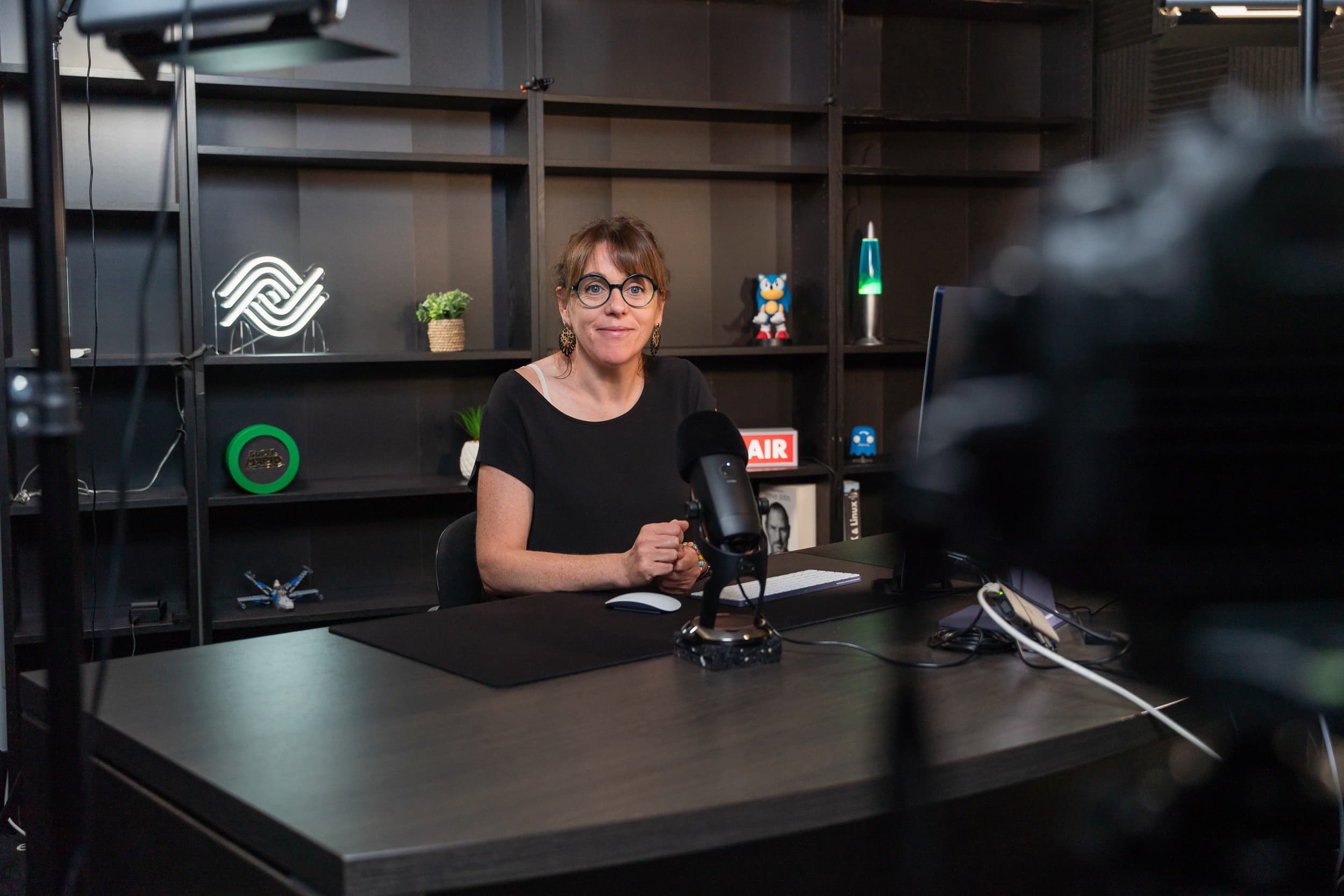 Seated woman smiling at a camera filming her in a professional video studio for the Ephoto Dam photo library solution.