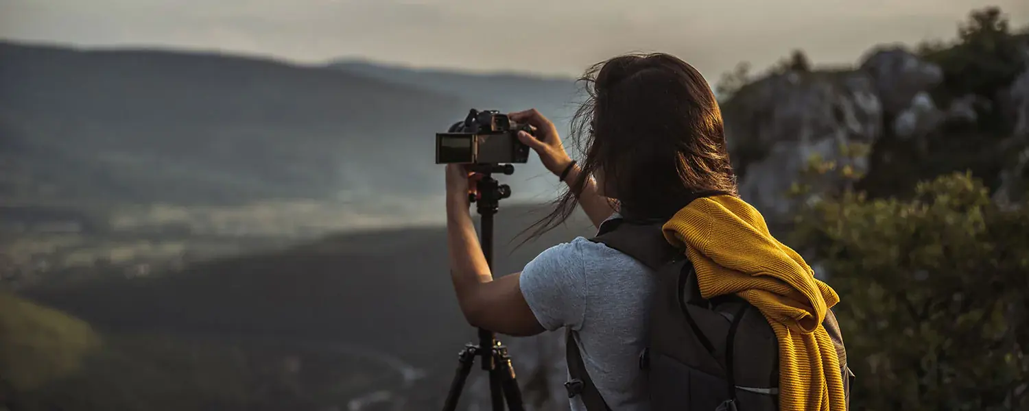 Woman holding a camera on a tripod, taking a photo of the panorama.