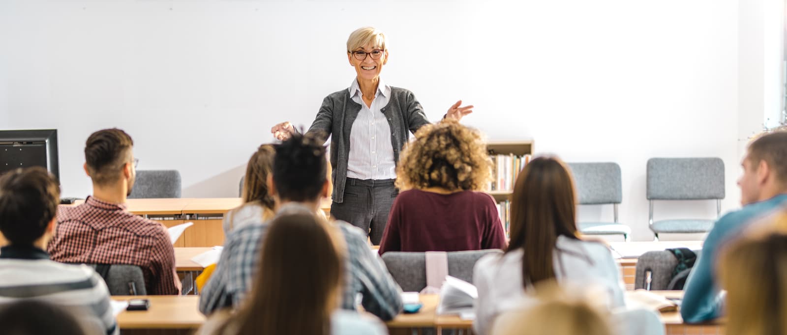 Teacher talking in front of pupils and moving her arms to attract attention.