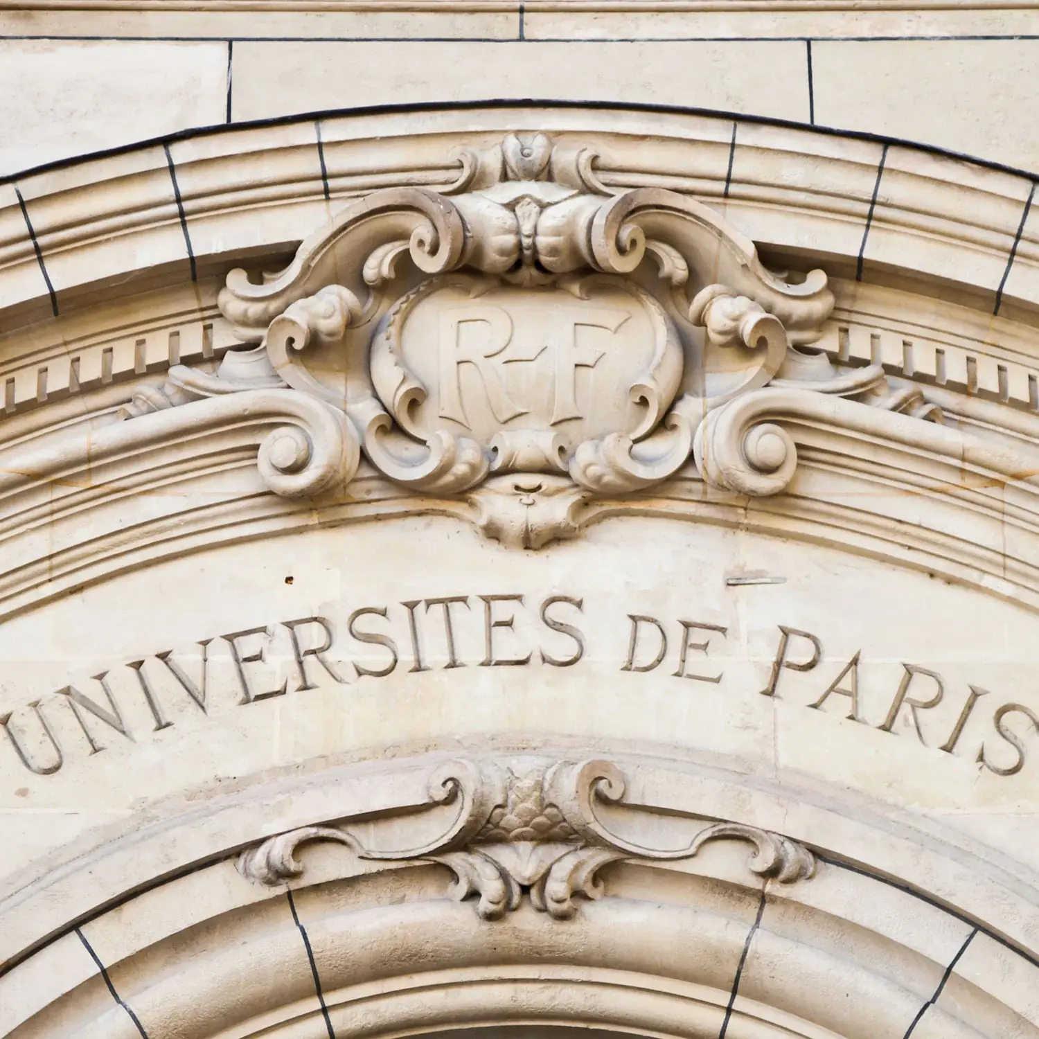Facade of a stone building with writing in the stone University